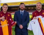 A photo of two Motherwell FC players and the Depute Leader Councillor Kelly with new Motherwell FC strips, showing the Suicide Prevention NL branding on the sleeves.