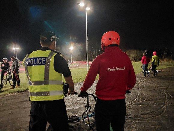Police Officer and Person with bike at night 