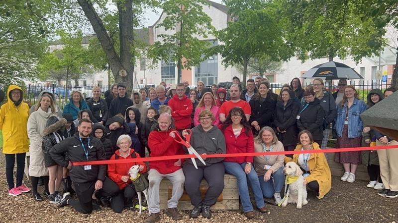 Group of people at community garden holding ribbon for official opening