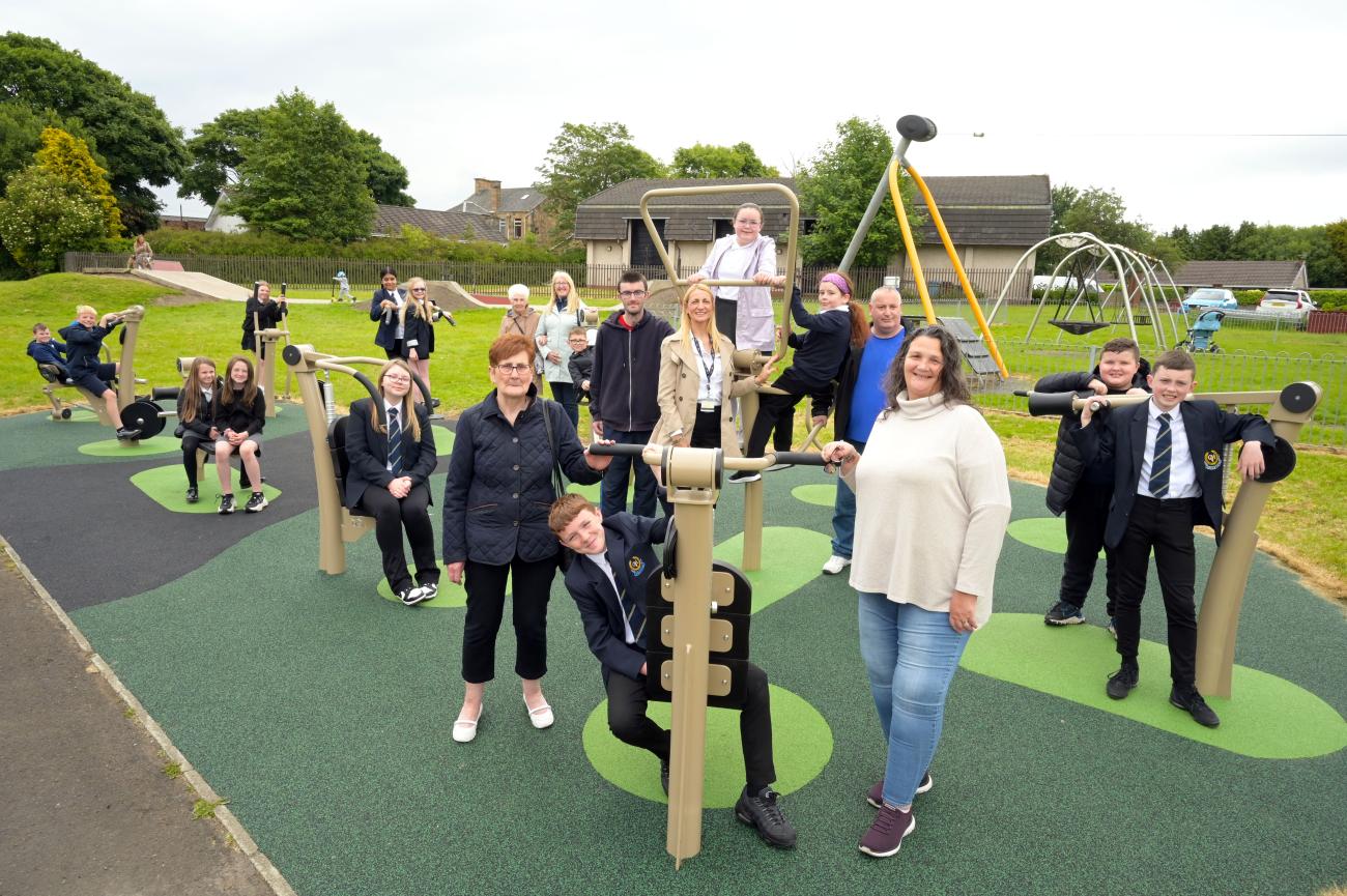 Adults and children standing smiling at new outdoor gym