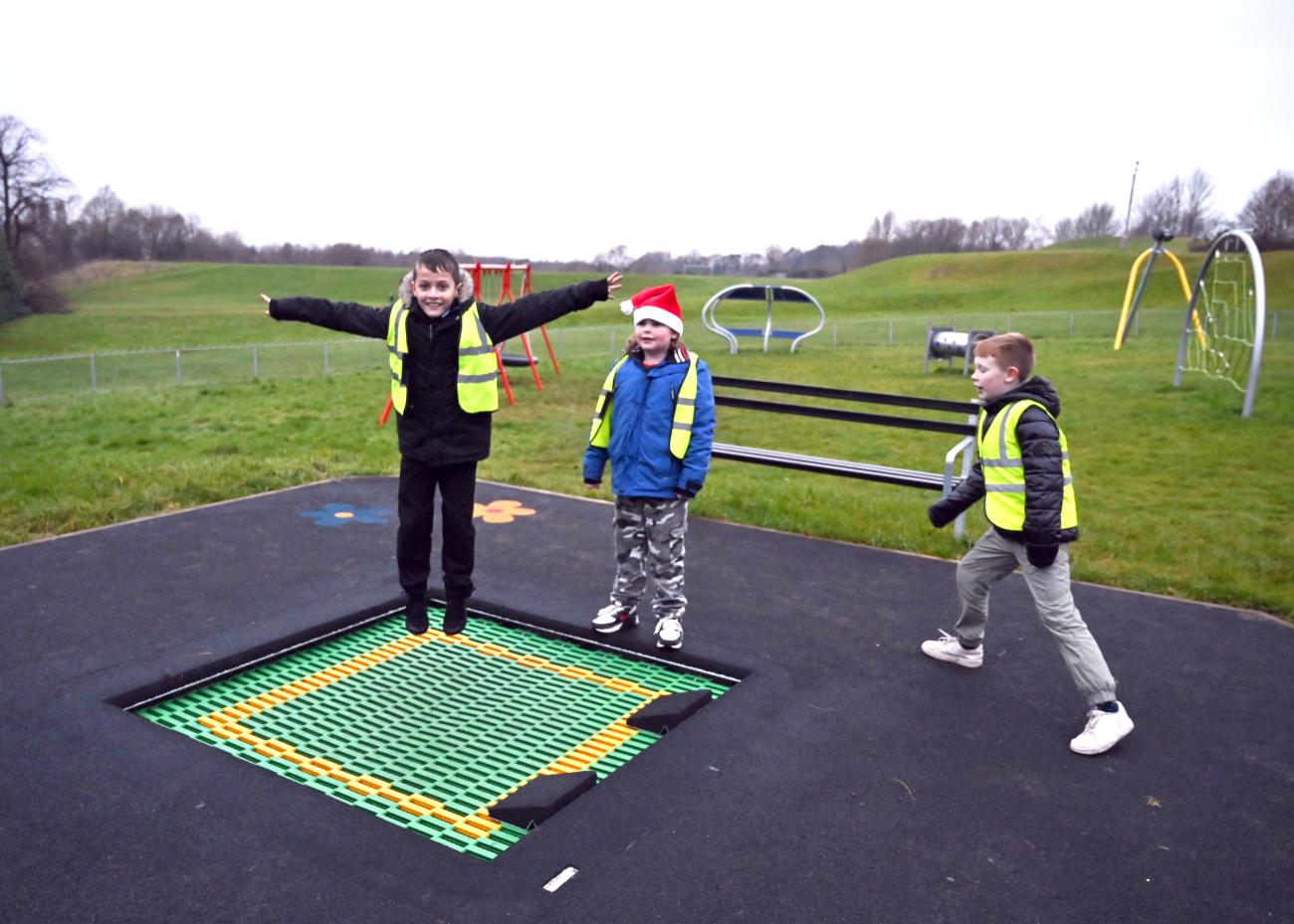 Children stand around built in trampoline on play park ground