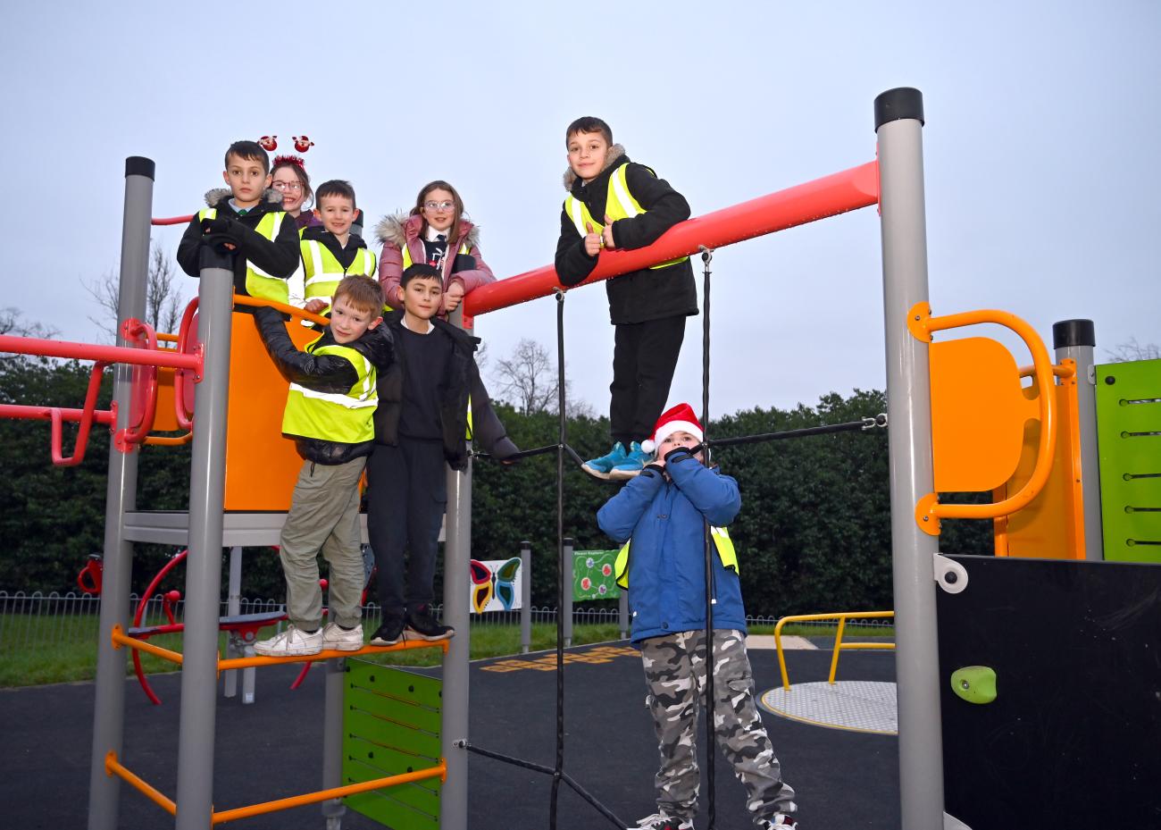Children stand on climbing frame inside play park 