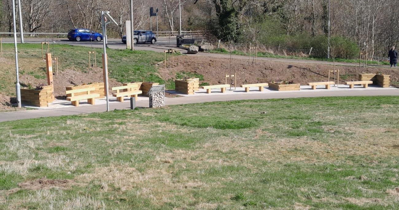 Grass in foreground with benches and planters in background