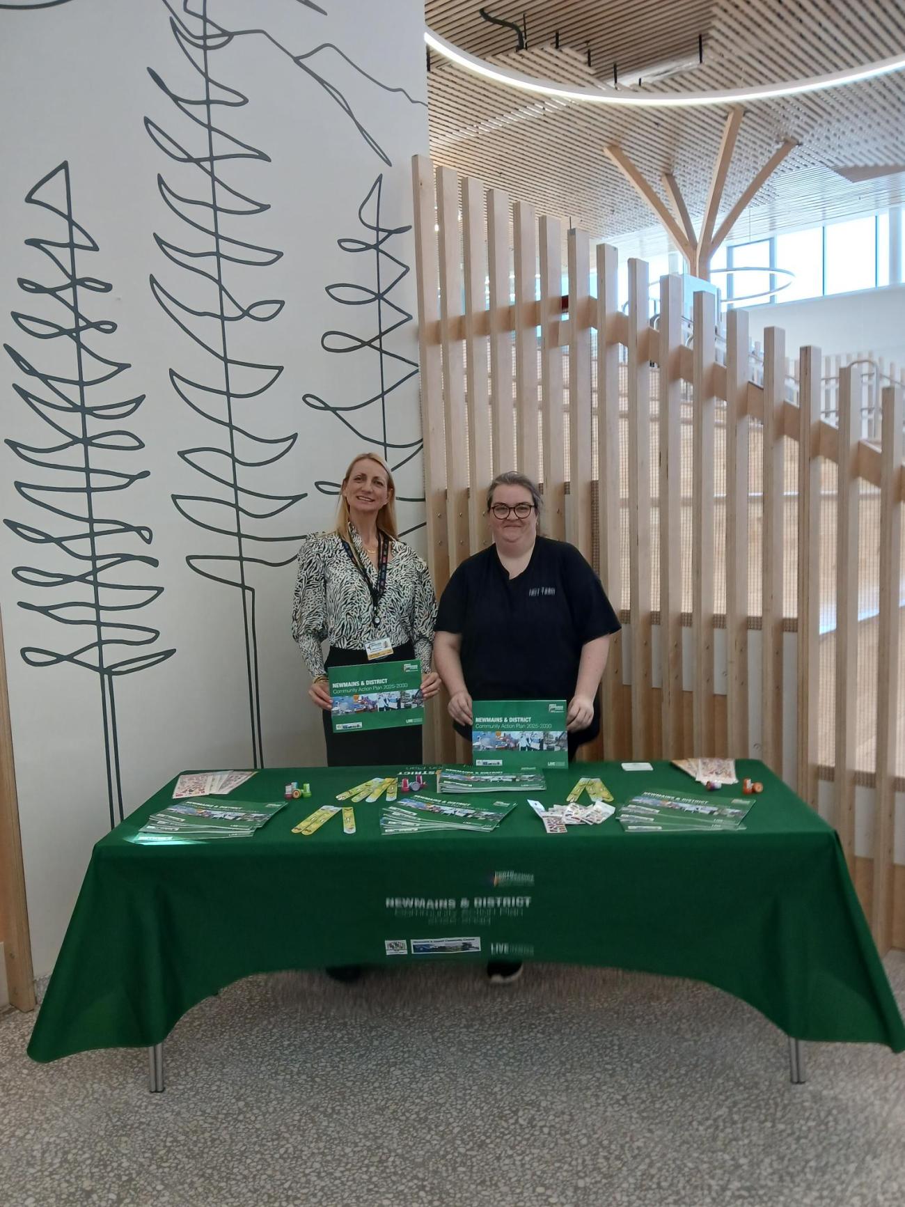 two people standing at table displaying newmains action plan