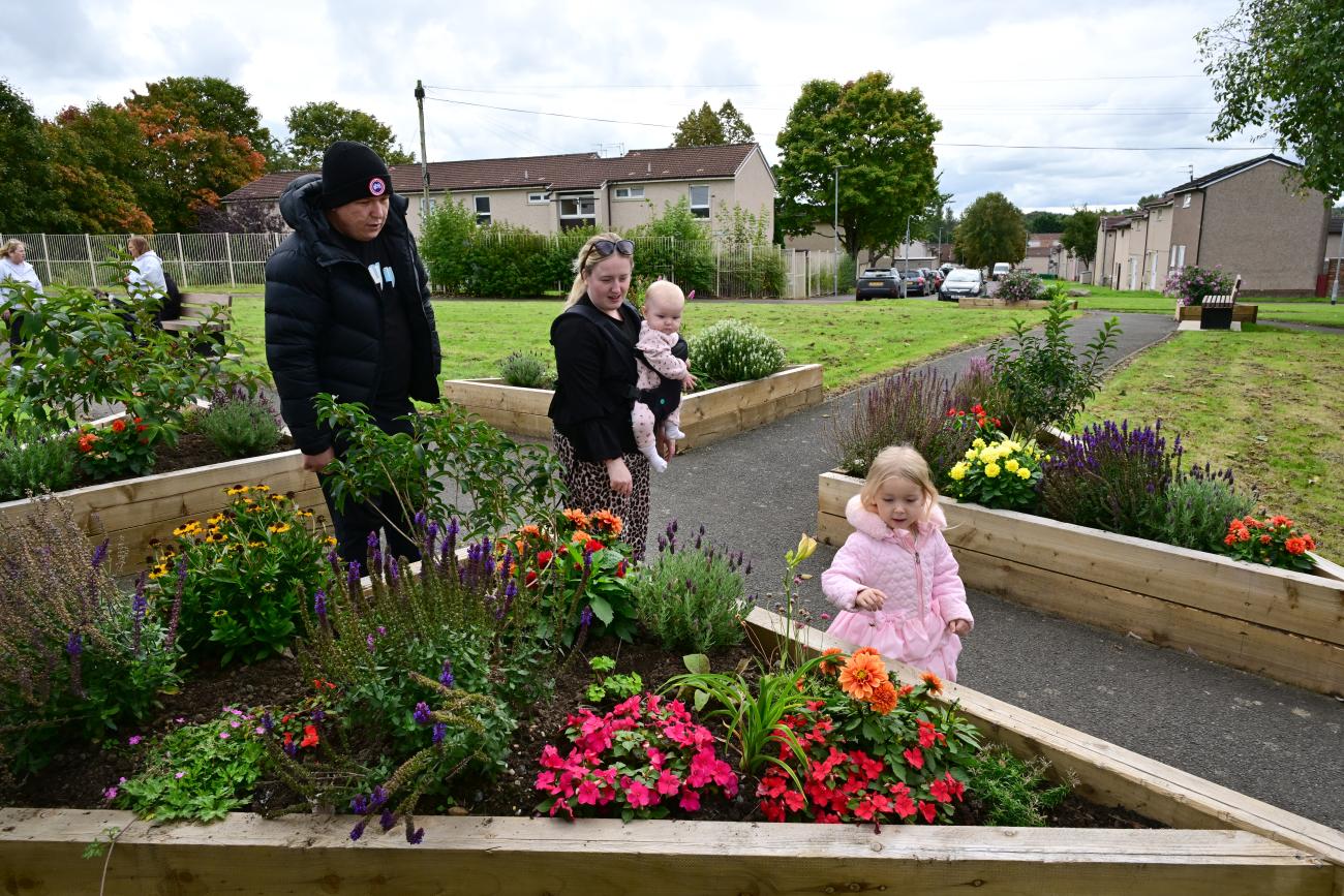 Community members walking around flower planters in community garden