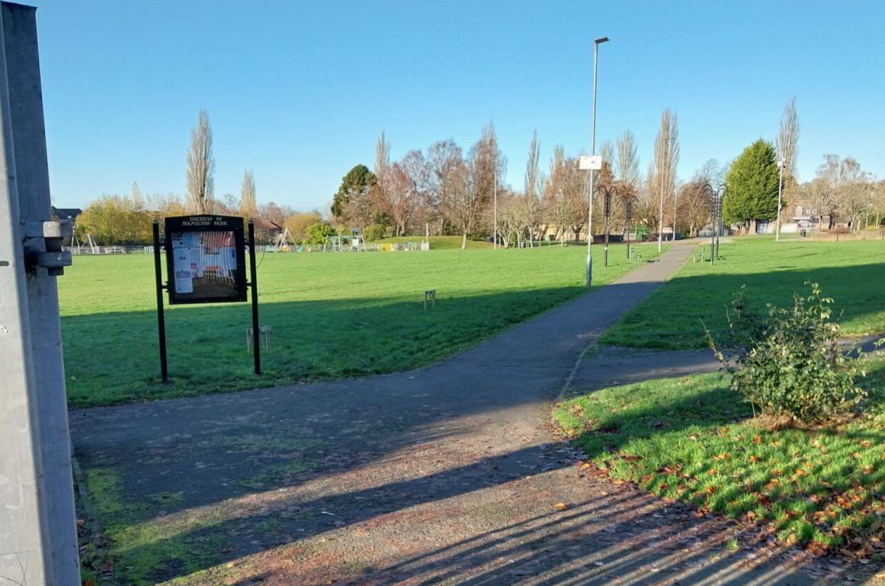 Walkway through park with noticeboard on display left hand side