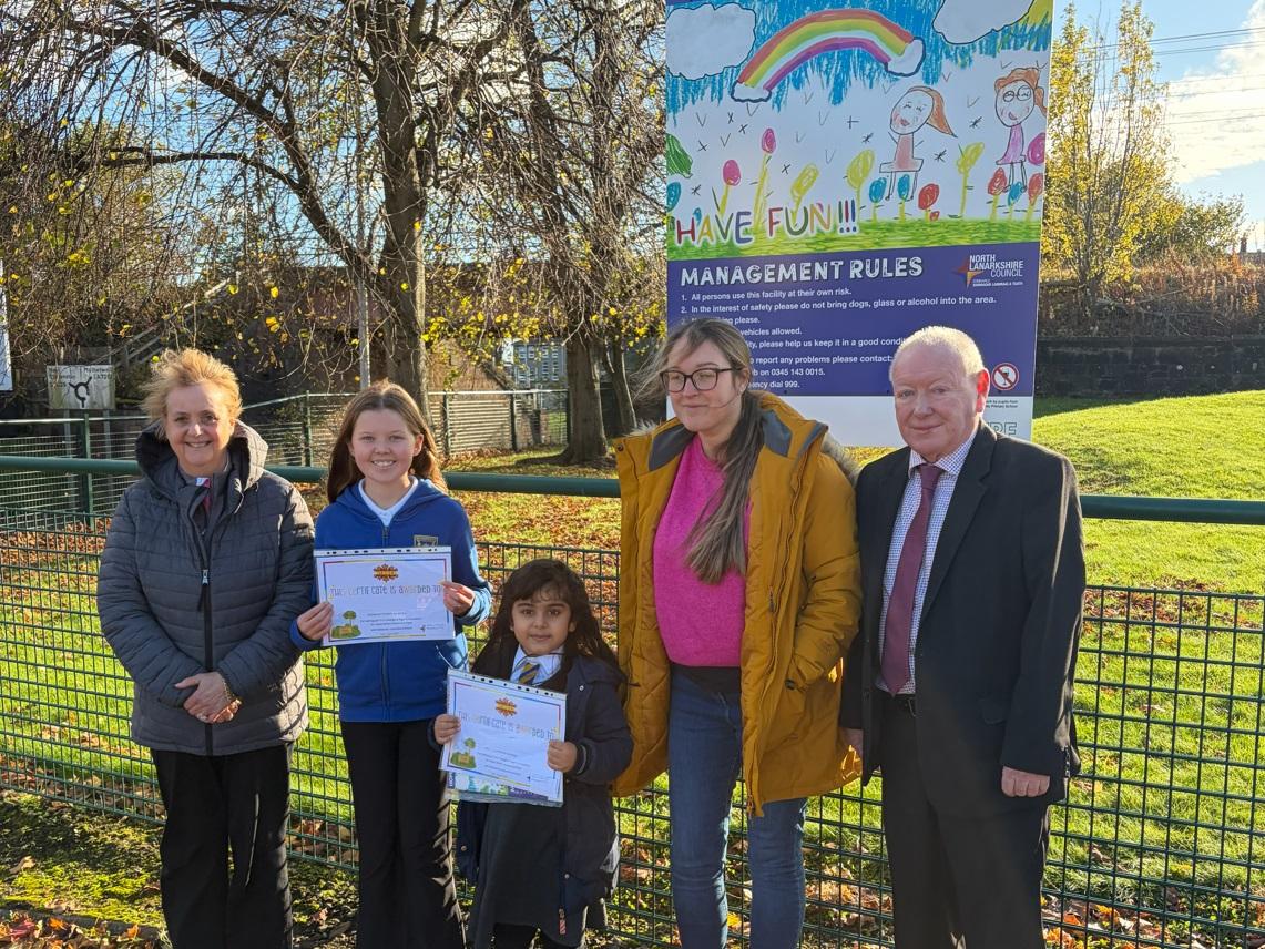 Two children pose with their certificates next to the Hope Street sign they helped design
