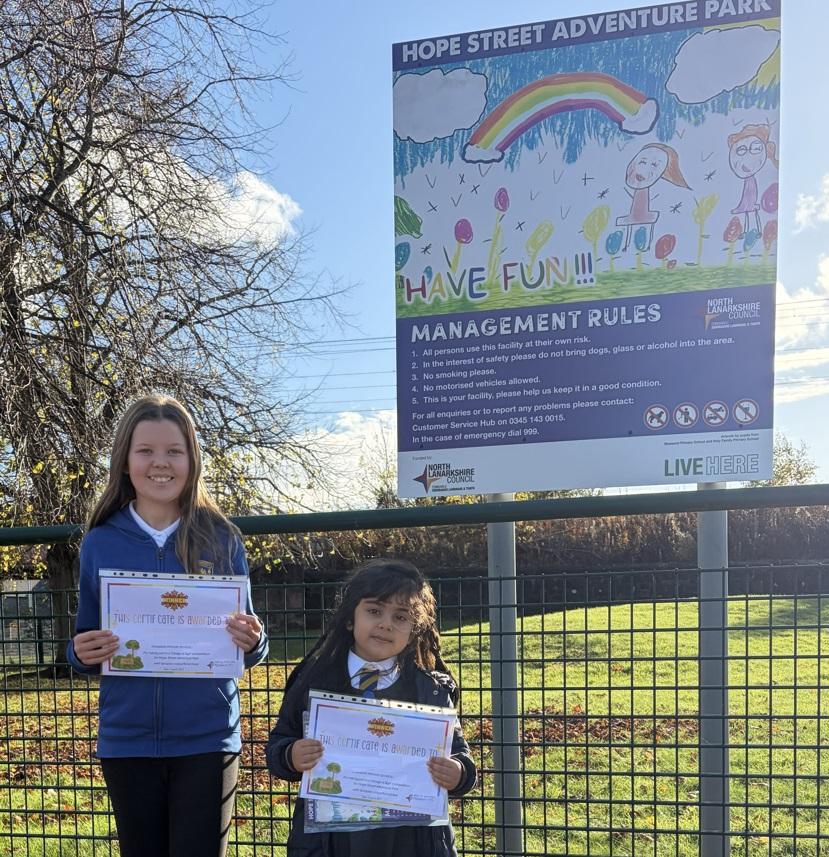 Two children pose with their certificates next to the Hope Street sign they helped design