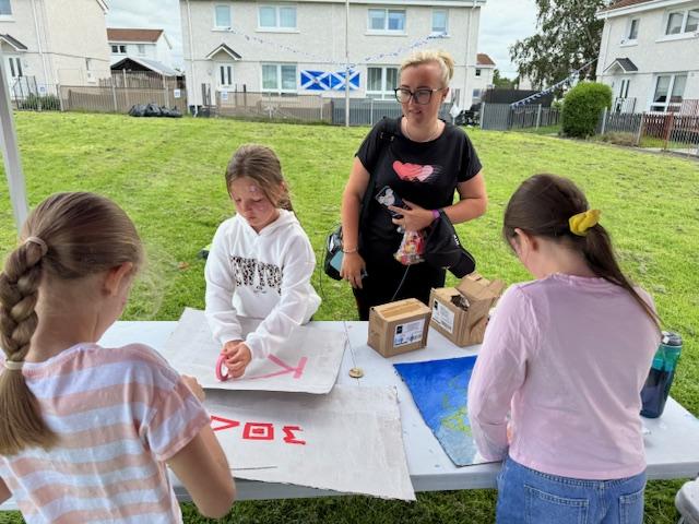 Children and adult interacting with table stall