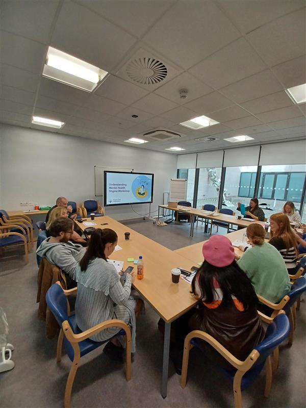 Group of people sitting around desks learning and discussing mental health issues