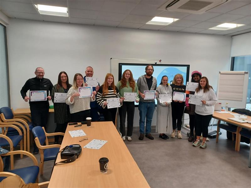People posing for group photo in a class/meeting room like setting