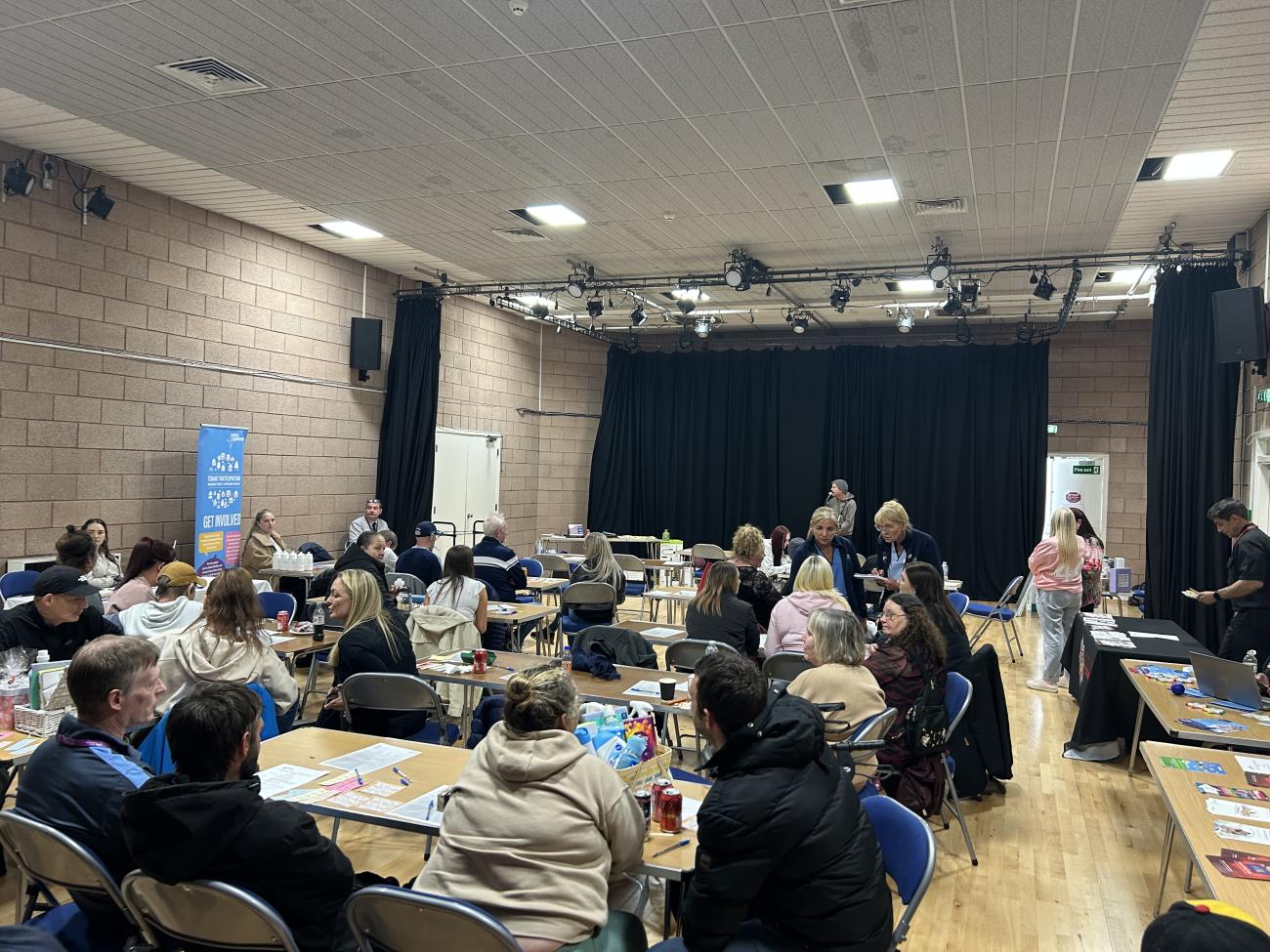 Community and service members in a hall awaiting a presentation