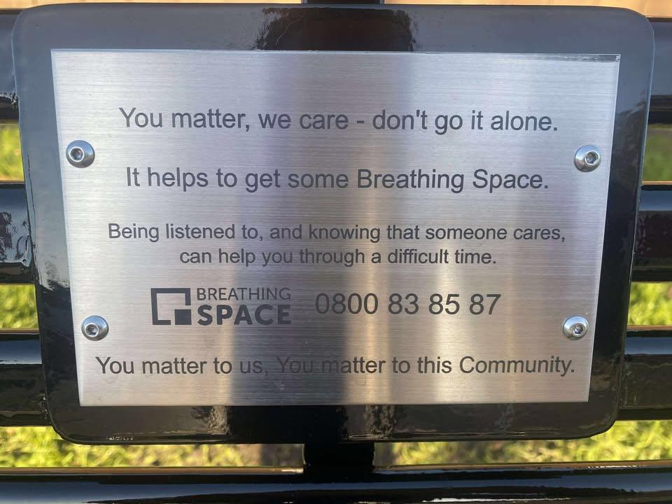 Close up of bench plaque, Inscription reads 'You matter, we care - don't go it alone. It helps to get some Breathing Space. Being listened to, and knowing that someone cares, can help you through a difficult time. Breathing Space 0800 83 85 87. You matter to us, you matter to this community' 