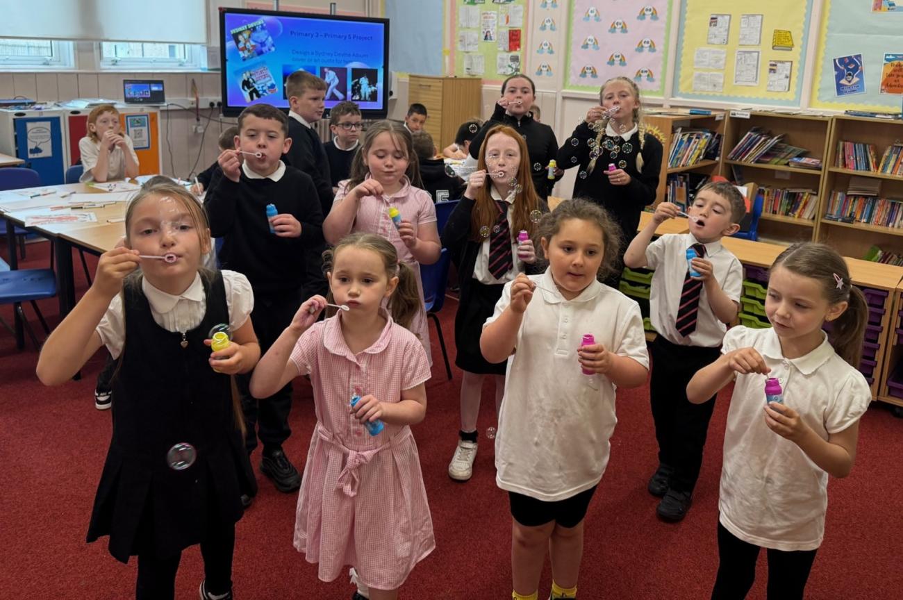 Pupils blowing bubbles for photograph