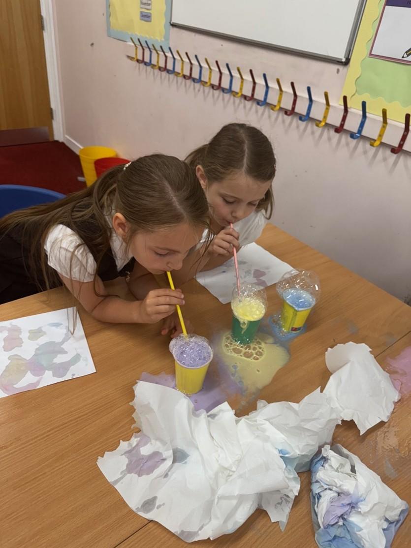 Two pupils at desk blowing bubbles