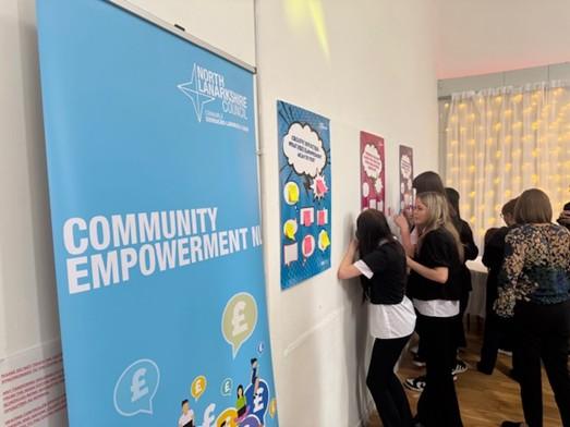 Community empowerment banner in forefront with students from St Aidan's High School to the side