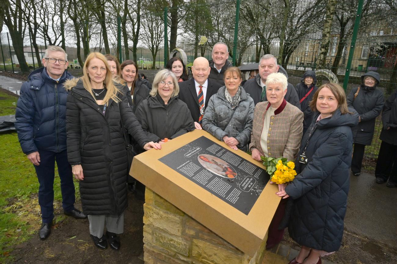 Members of NLC and Sydney Devine's family standing beside memorial plaque