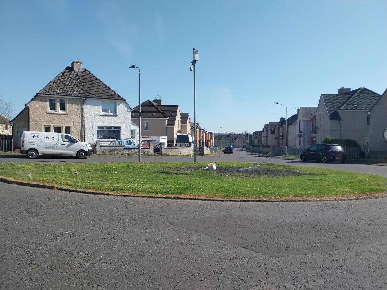 A small road with an island of grass in the middle separating from another road