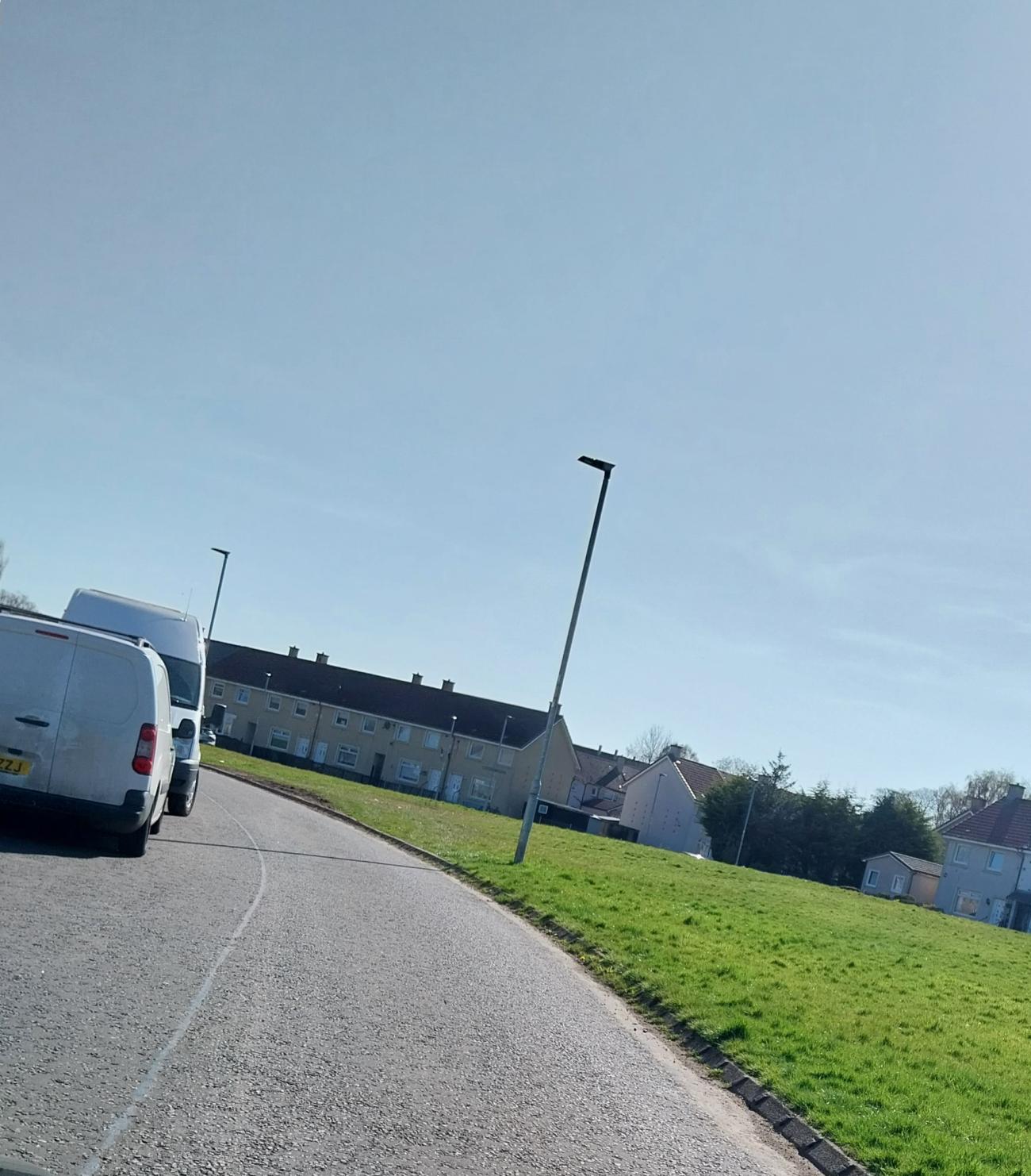 A tight road on a slight bend with cars parked allowing only use of one side of road