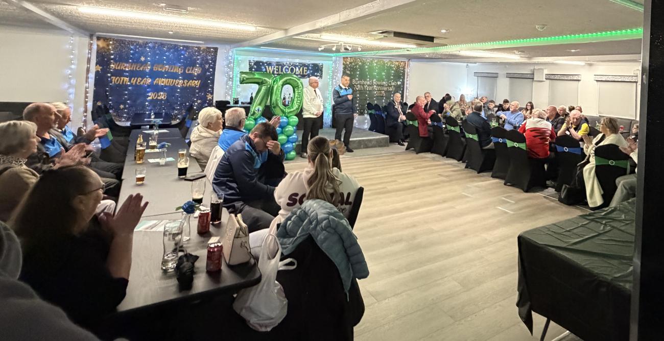 A person speaking in front of a seated crowd in Burnhead Centre