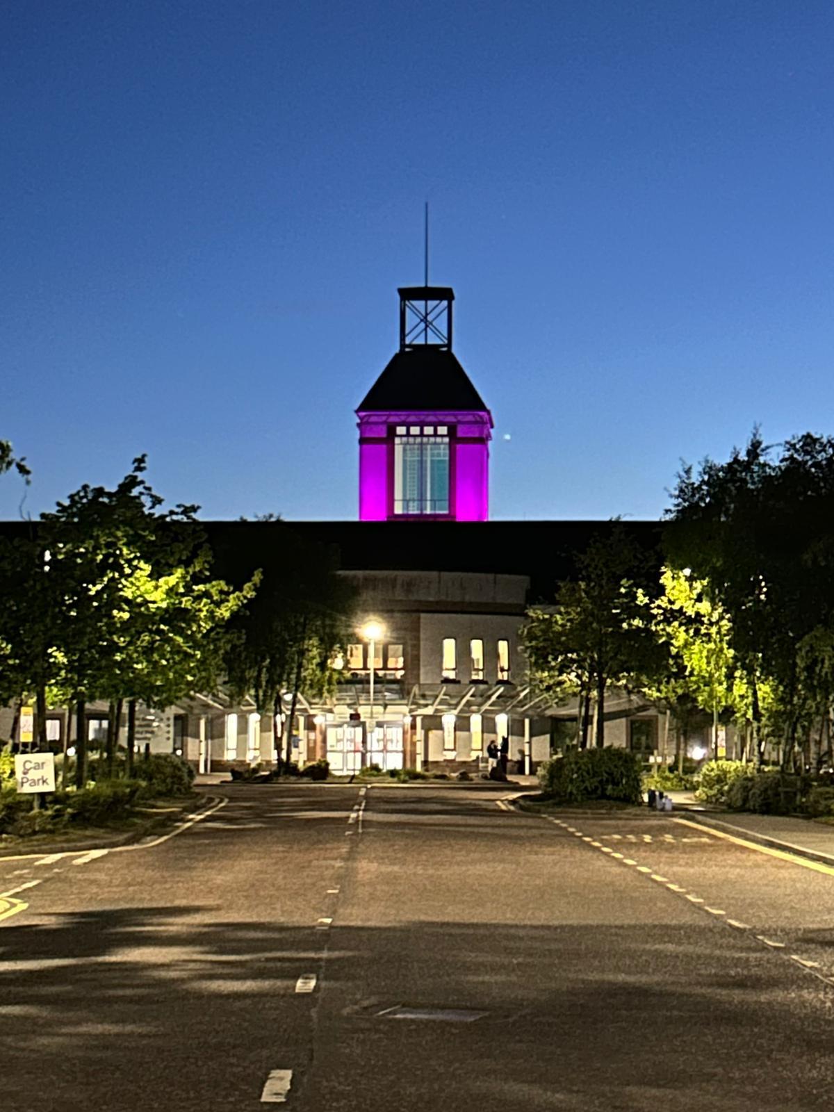Wishaw Hospital at night with the spire lit up pink in support of mental health week
