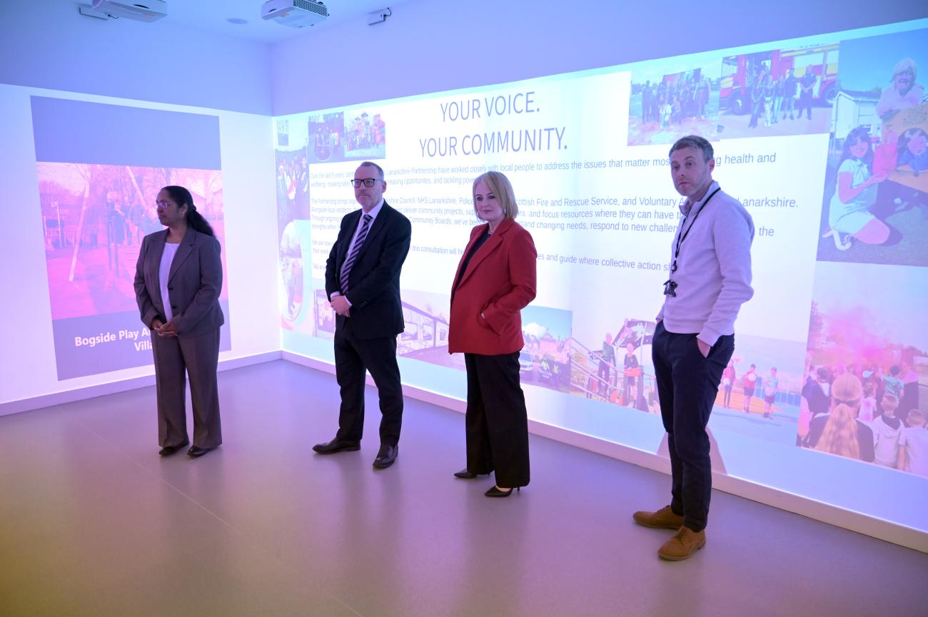 adults standing in room with images on walls