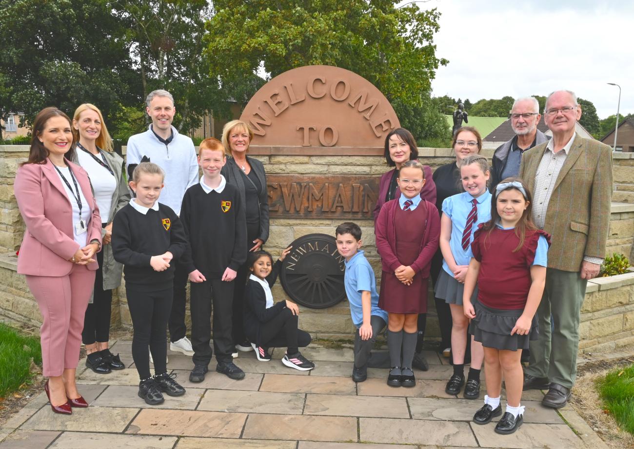 School pupils pose beside the welcome to Newmains sign