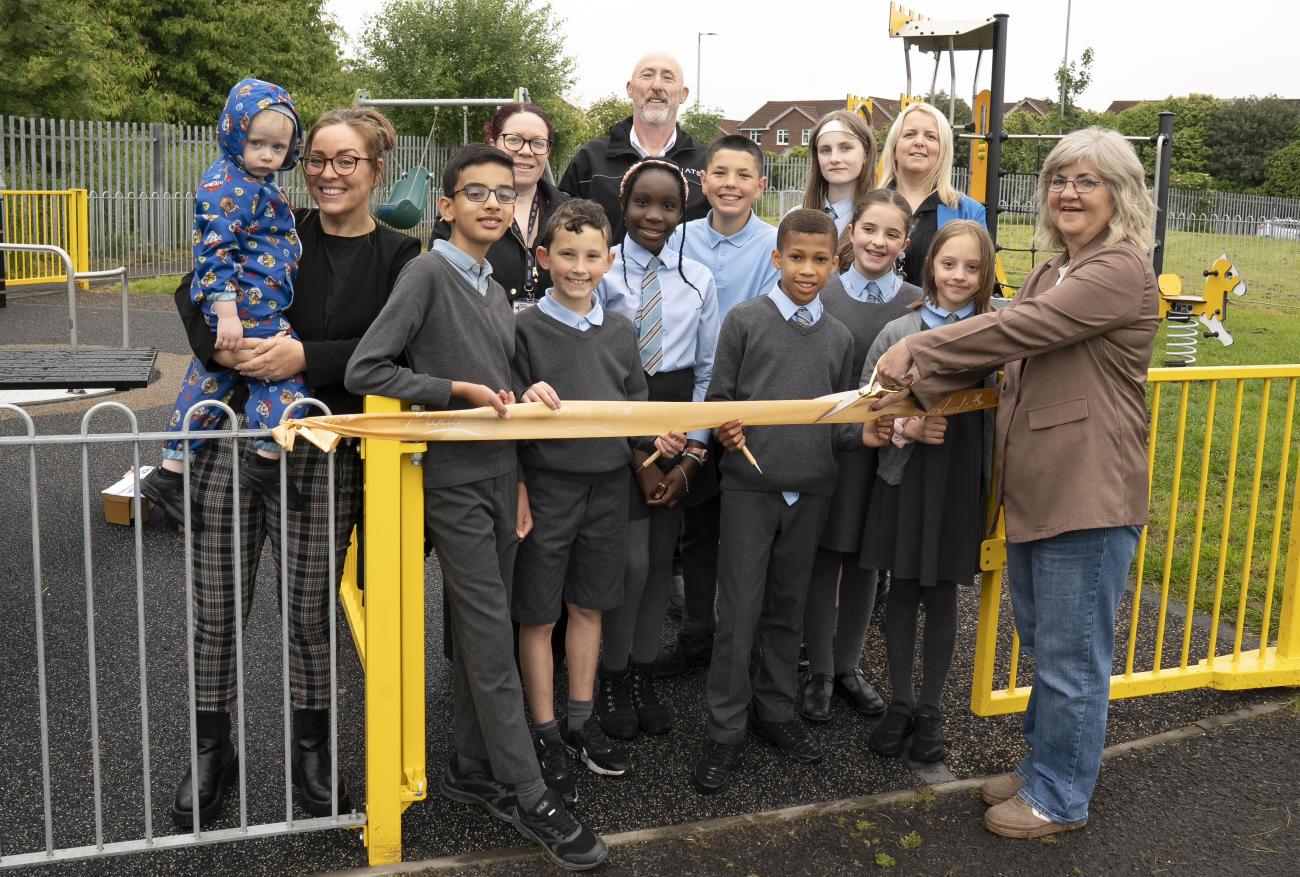 Children and adults cutting ribbon to open new play area