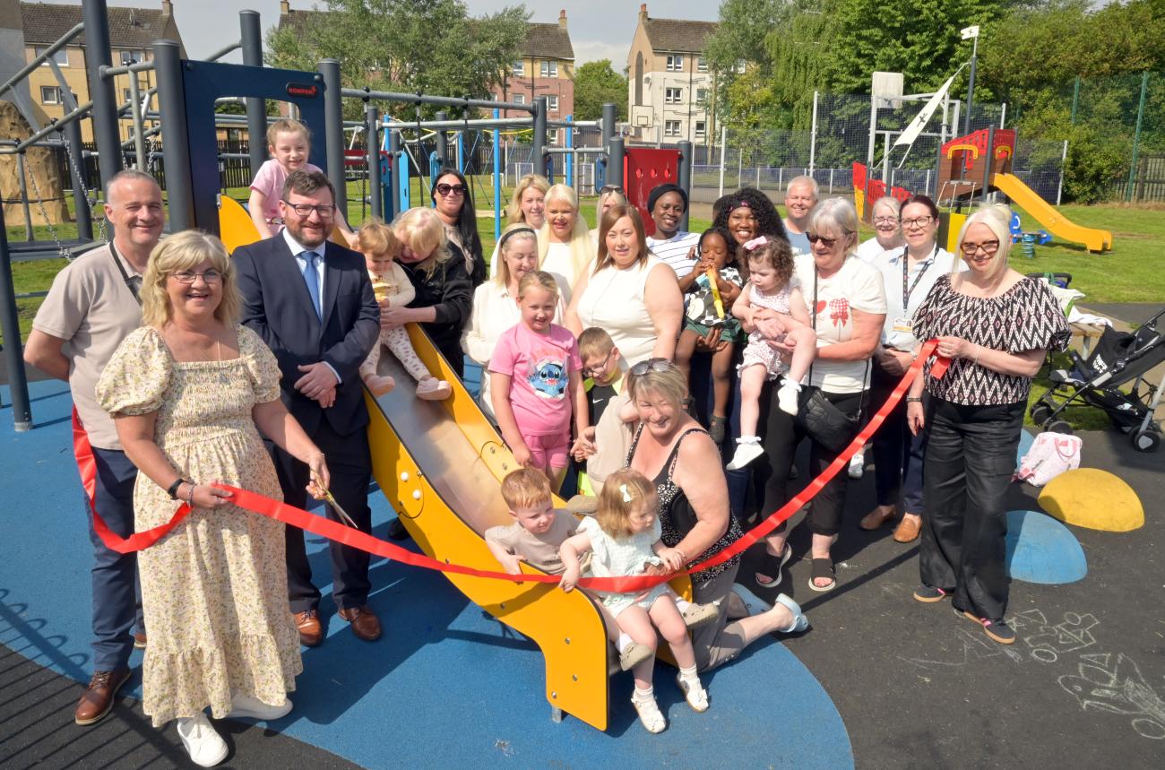 children and adults cutting ribbon to open play area