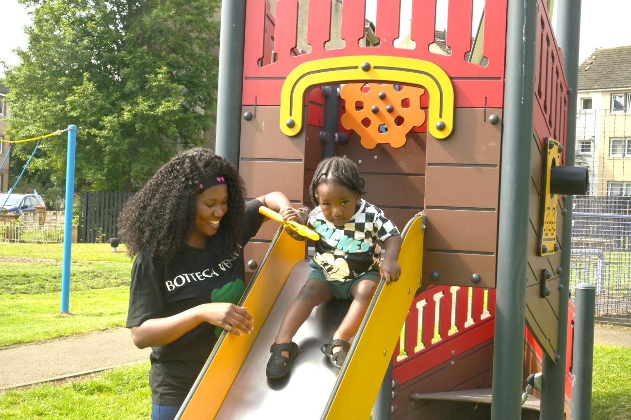 child on slide with adult looking on