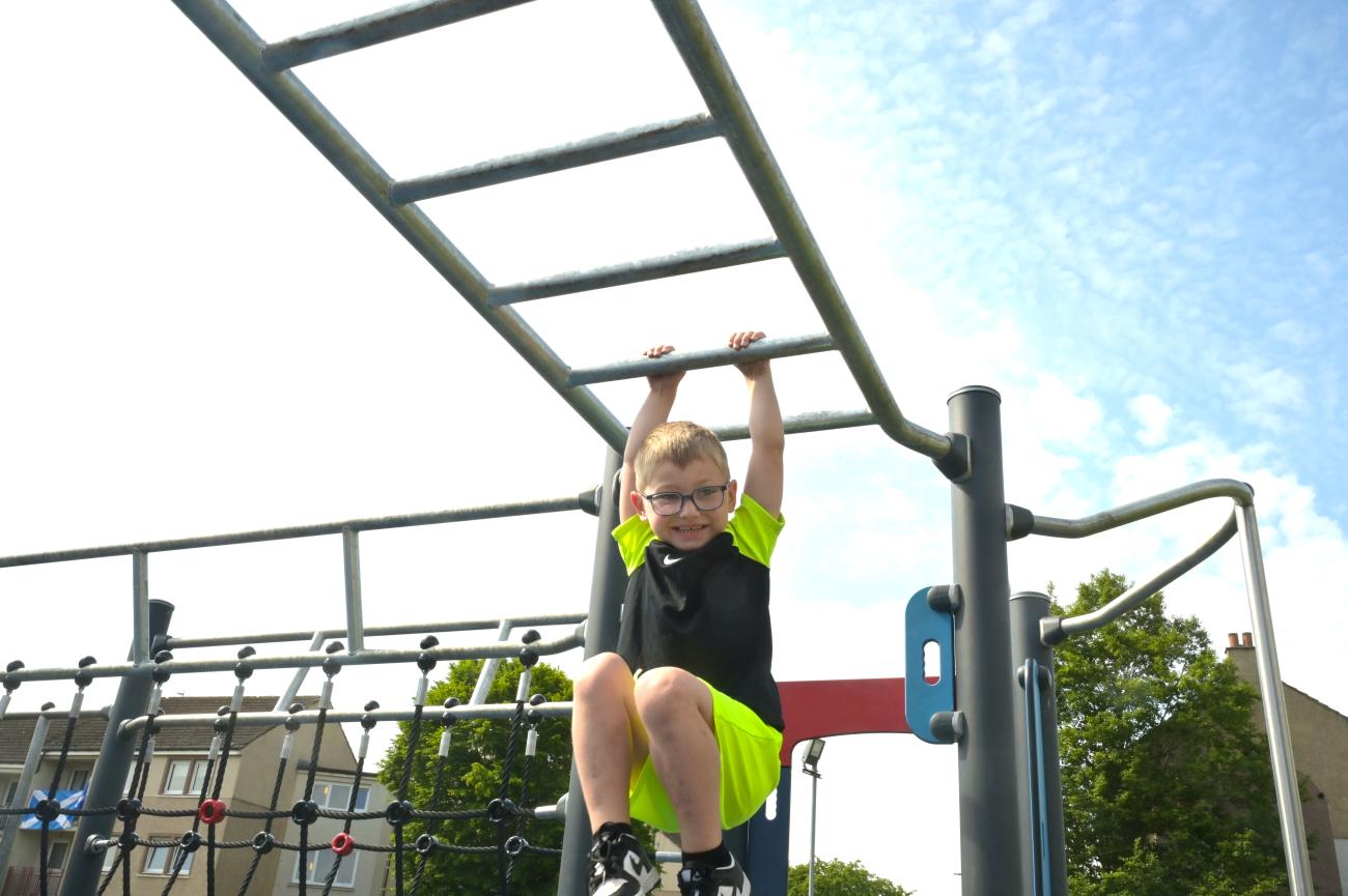 child swinging from bars on play equipment