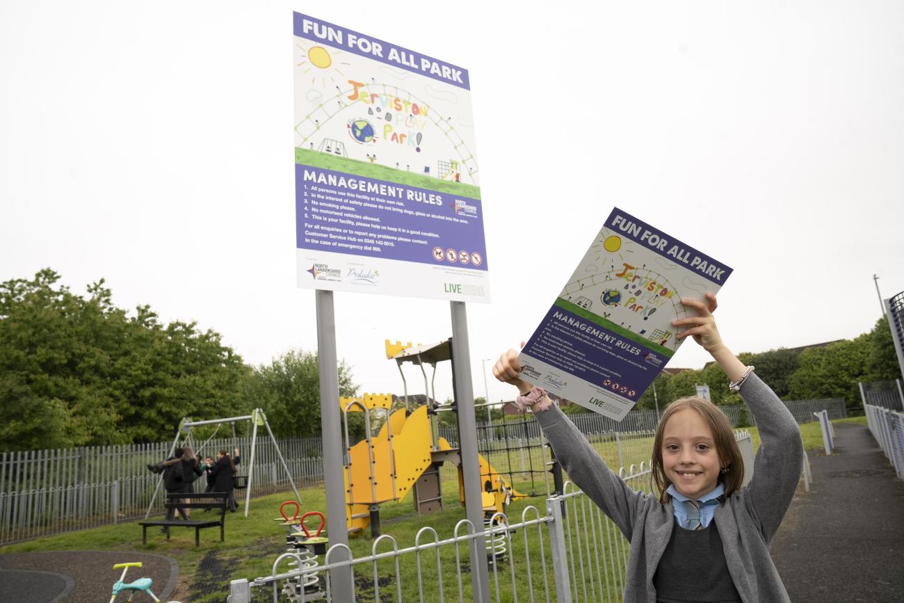 Child holding sign of new play area